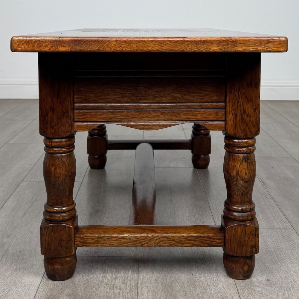A dark oak rectangular coffee table featuring two front drawers with wooden knob handles and turned baluster legs connected by a low stretcher. View III