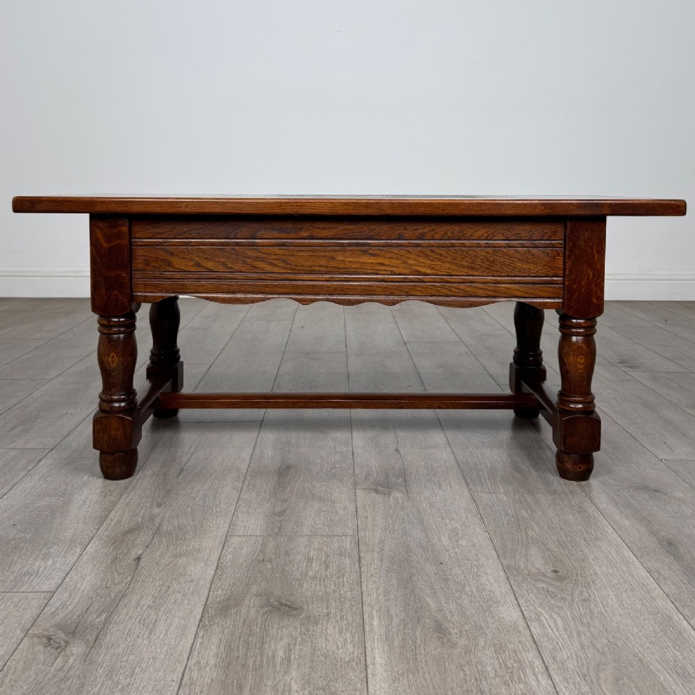 A dark oak rectangular coffee table featuring two front drawers with wooden knob handles and turned baluster legs connected by a low stretcher. View V
