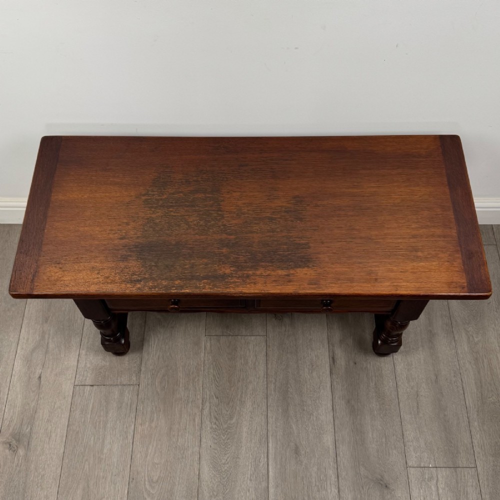 A dark oak rectangular coffee table featuring two front drawers with wooden knob handles and turned baluster legs connected by a low stretcher. View IX