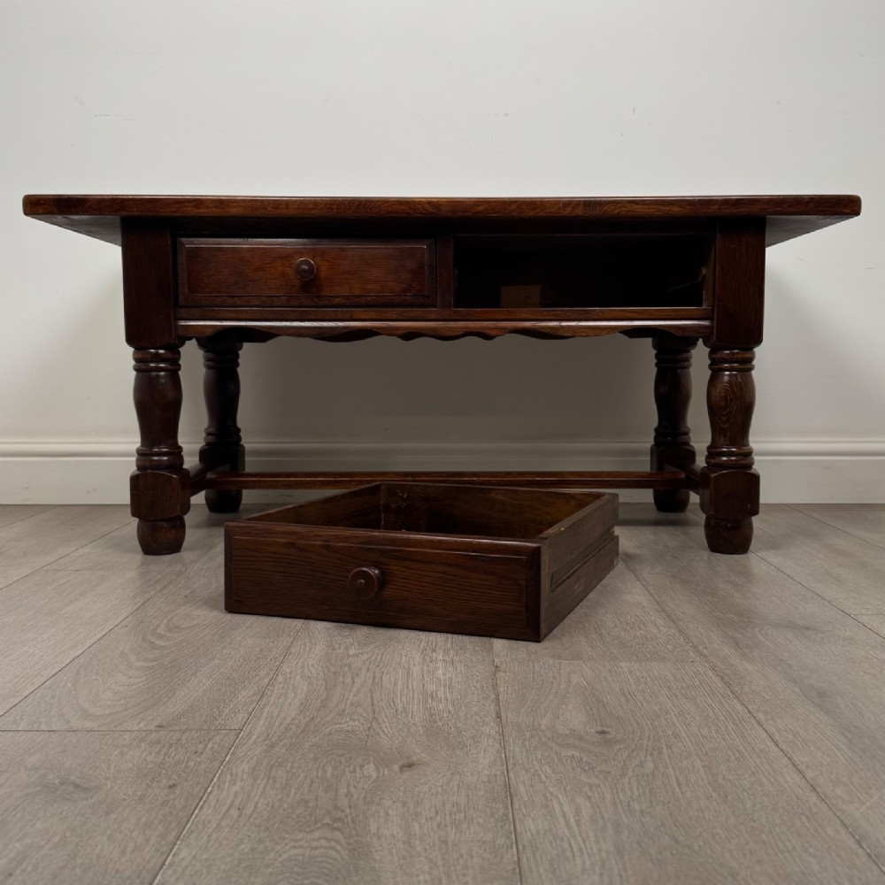 A dark oak rectangular coffee table featuring two front drawers with wooden knob handles and turned baluster legs connected by a low stretcher. View X