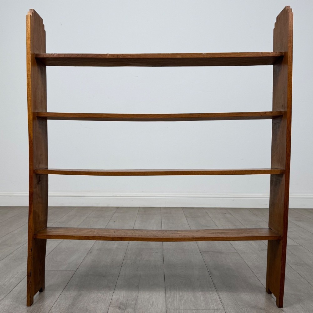 An open-backed 20th-century Arts and Crafts walnut bookcase with four horizontal shelves and notched top end supports.