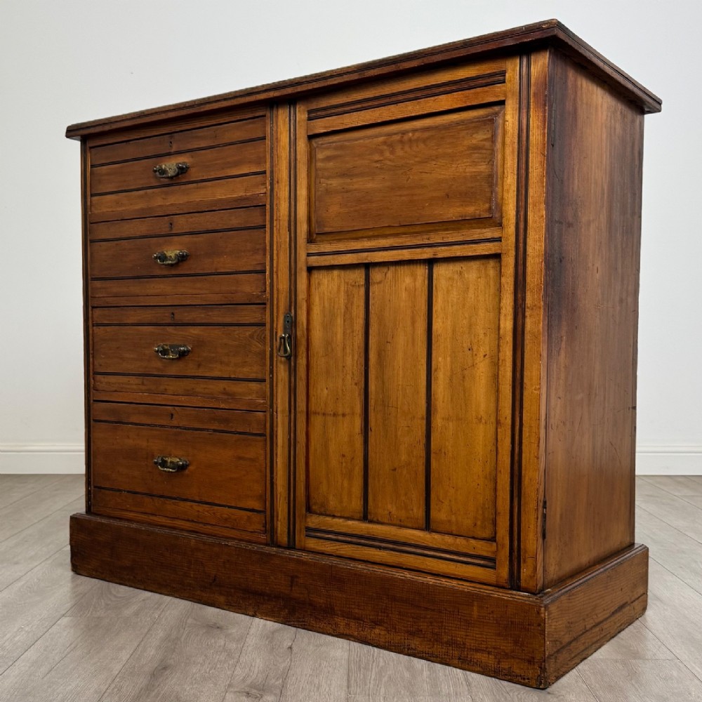 A nineteenth-century warm brown ash wood cupboard featuring four drawers on the left and a panelled cupboard door on the right resting on a plinth base. View III