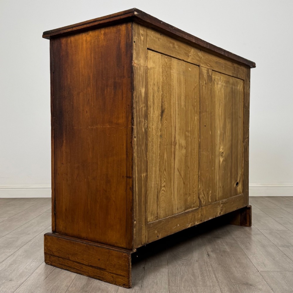 A nineteenth-century warm brown ash wood cupboard featuring four drawers on the left and a panelled cupboard door on the right resting on a plinth base. View V