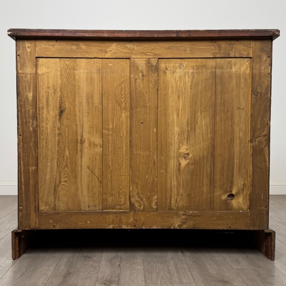A nineteenth-century warm brown ash wood cupboard featuring four drawers on the left and a panelled cupboard door on the right resting on a plinth base. View VI
