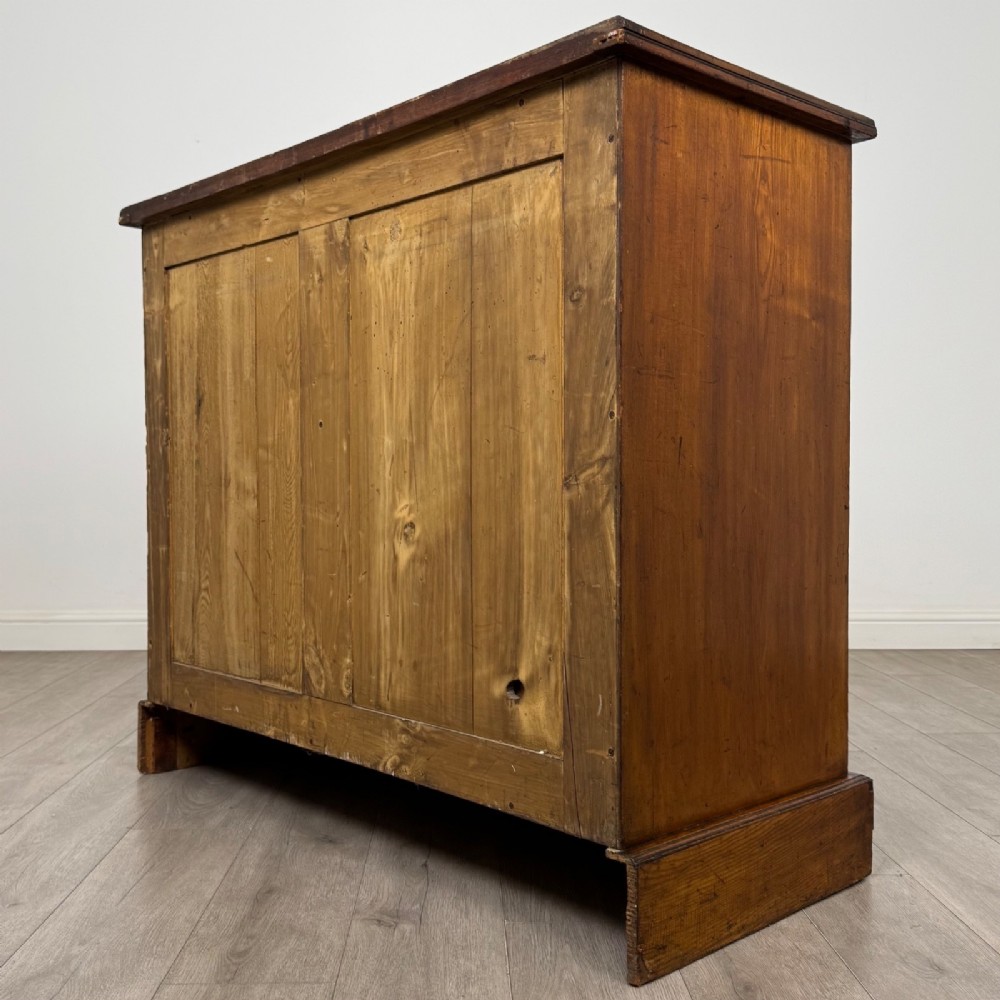A nineteenth-century warm brown ash wood cupboard featuring four drawers on the left and a panelled cupboard door on the right resting on a plinth base. View VII
