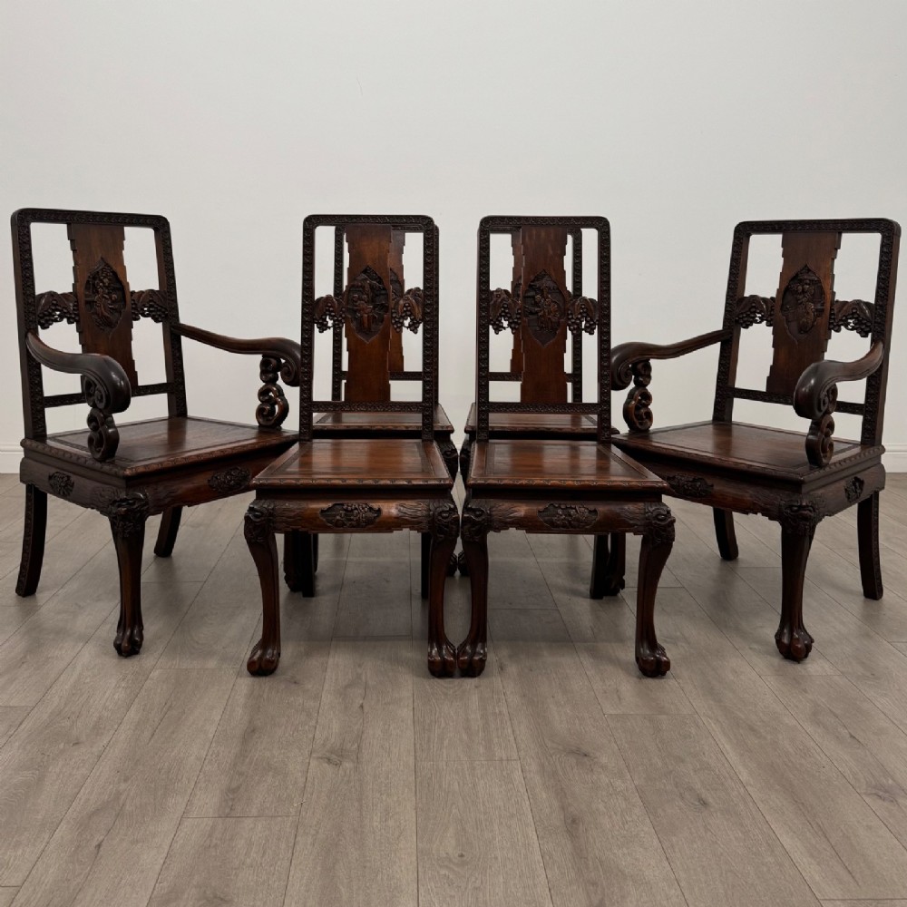A set of six antique dark rosewood Chinese dining chairs featuring carved back splats, scroll armrests on carvers, carved aprons, and claw feet.