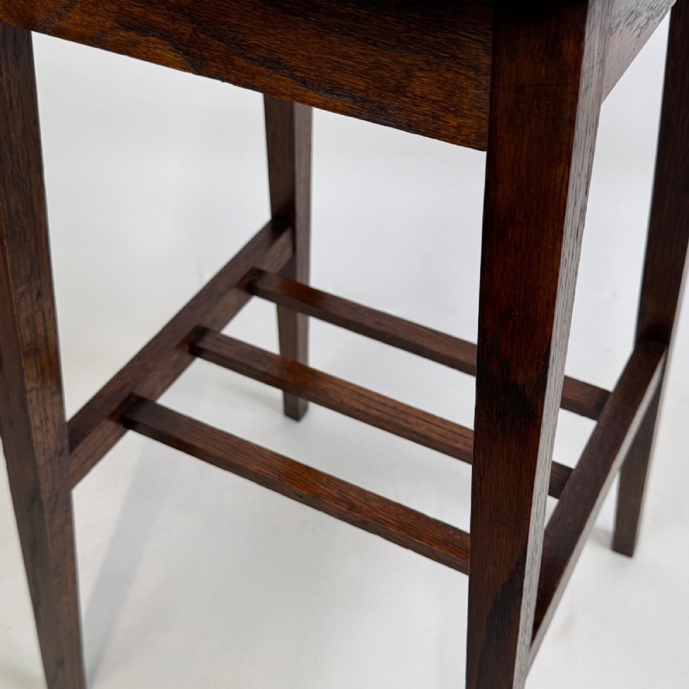 A tall, dark oak Edwardian side table featuring a scalloped piecrust rim top, four splayed square legs, and a lower slatted shelf. View VIII