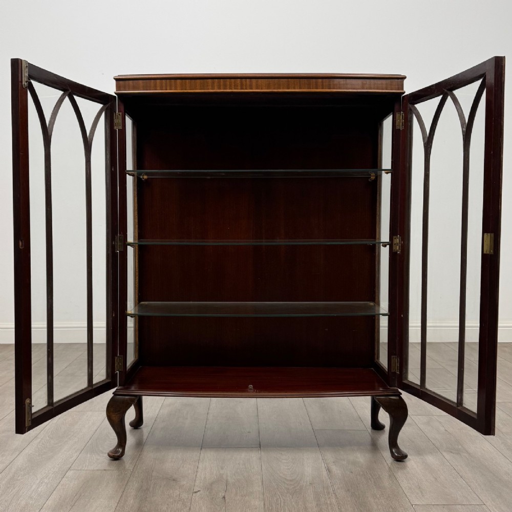 An Edwardian mahogany display cabinet featuring astragal glazed doors with gothic arches, interior glass shelves, and cabriole legs. View II