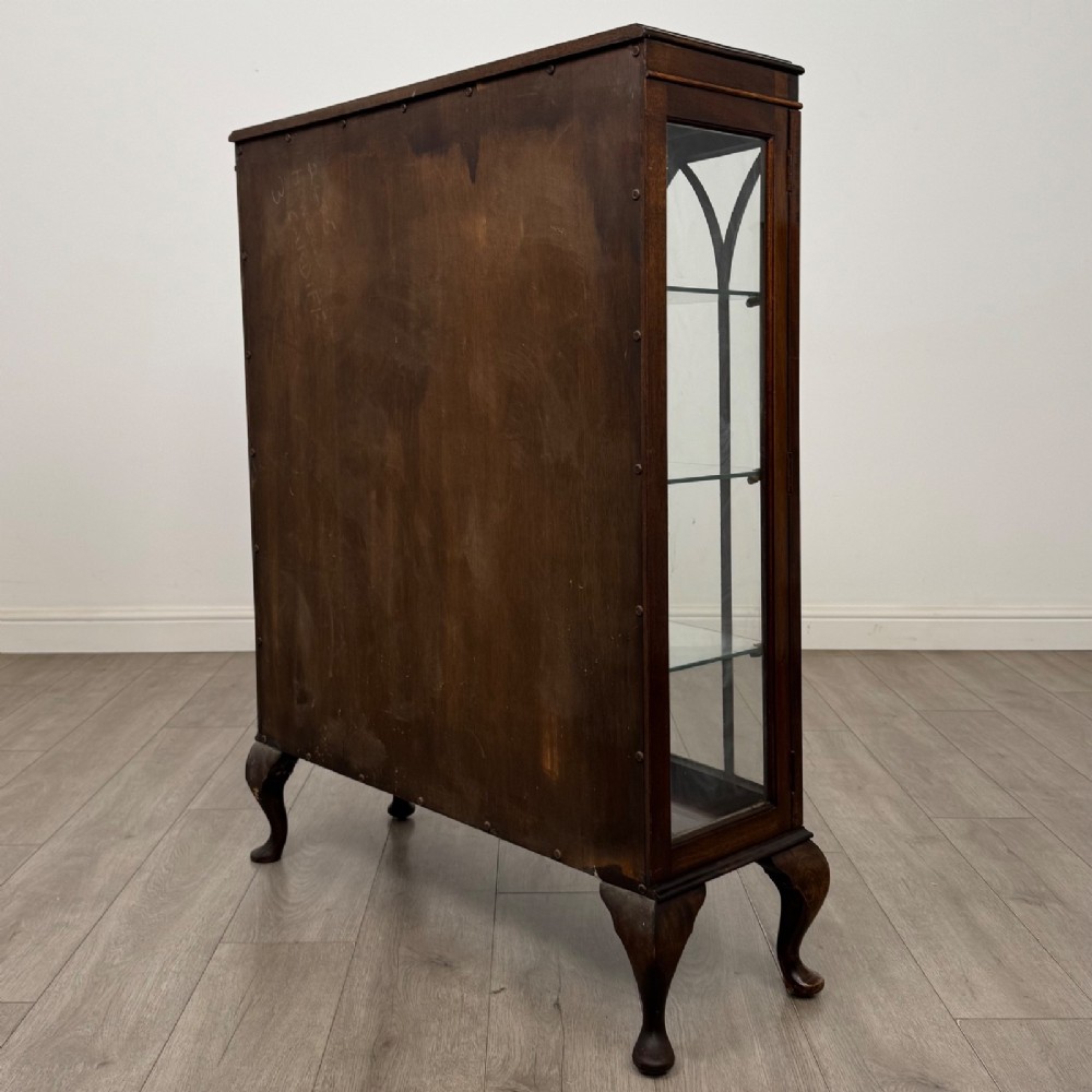 An Edwardian mahogany display cabinet featuring astragal glazed doors with gothic arches, interior glass shelves, and cabriole legs. View VII