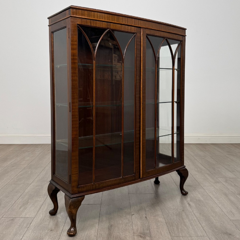 An Edwardian mahogany display cabinet featuring astragal glazed doors with gothic arches, interior glass shelves, and cabriole legs. View IX