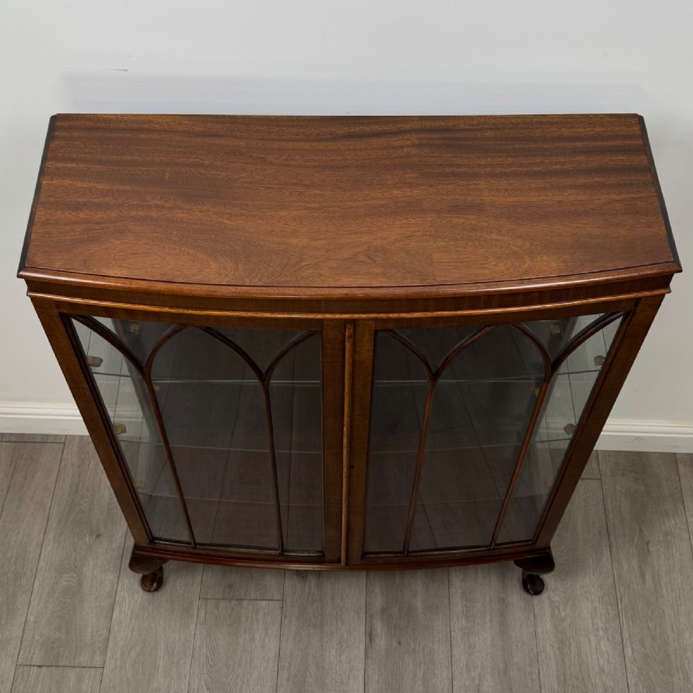 An Edwardian mahogany display cabinet featuring astragal glazed doors with gothic arches, interior glass shelves, and cabriole legs. View X
