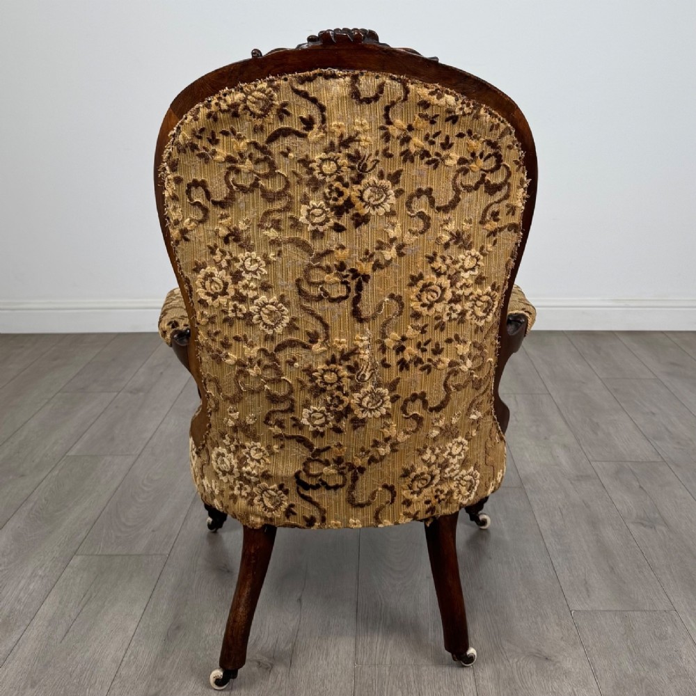 A 19th-century Victorian open armchair constructed from carved walnut wood and upholstered in a patterned gold and brown velvet fabric. View IV