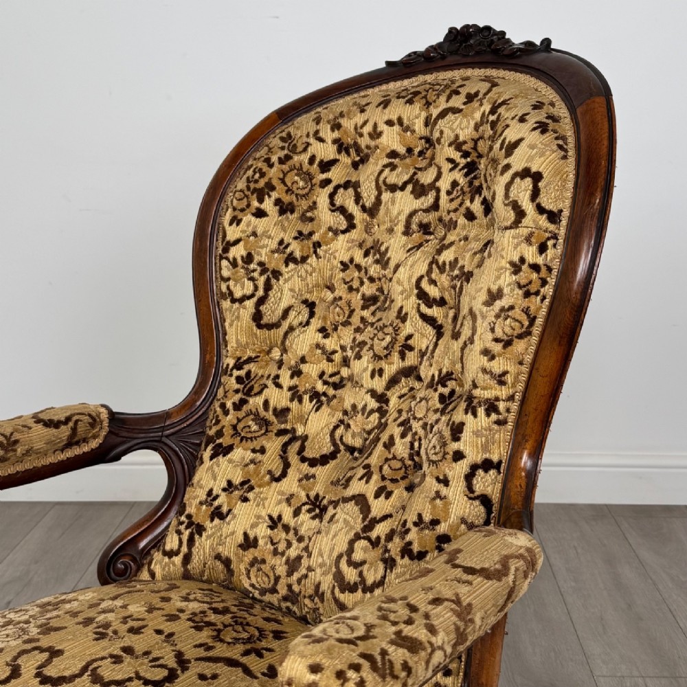 A 19th-century Victorian open armchair constructed from carved walnut wood and upholstered in a patterned gold and brown velvet fabric. View IX