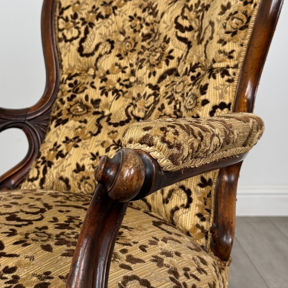 A 19th-century Victorian open armchair constructed from carved walnut wood and upholstered in a patterned gold and brown velvet fabric. View X