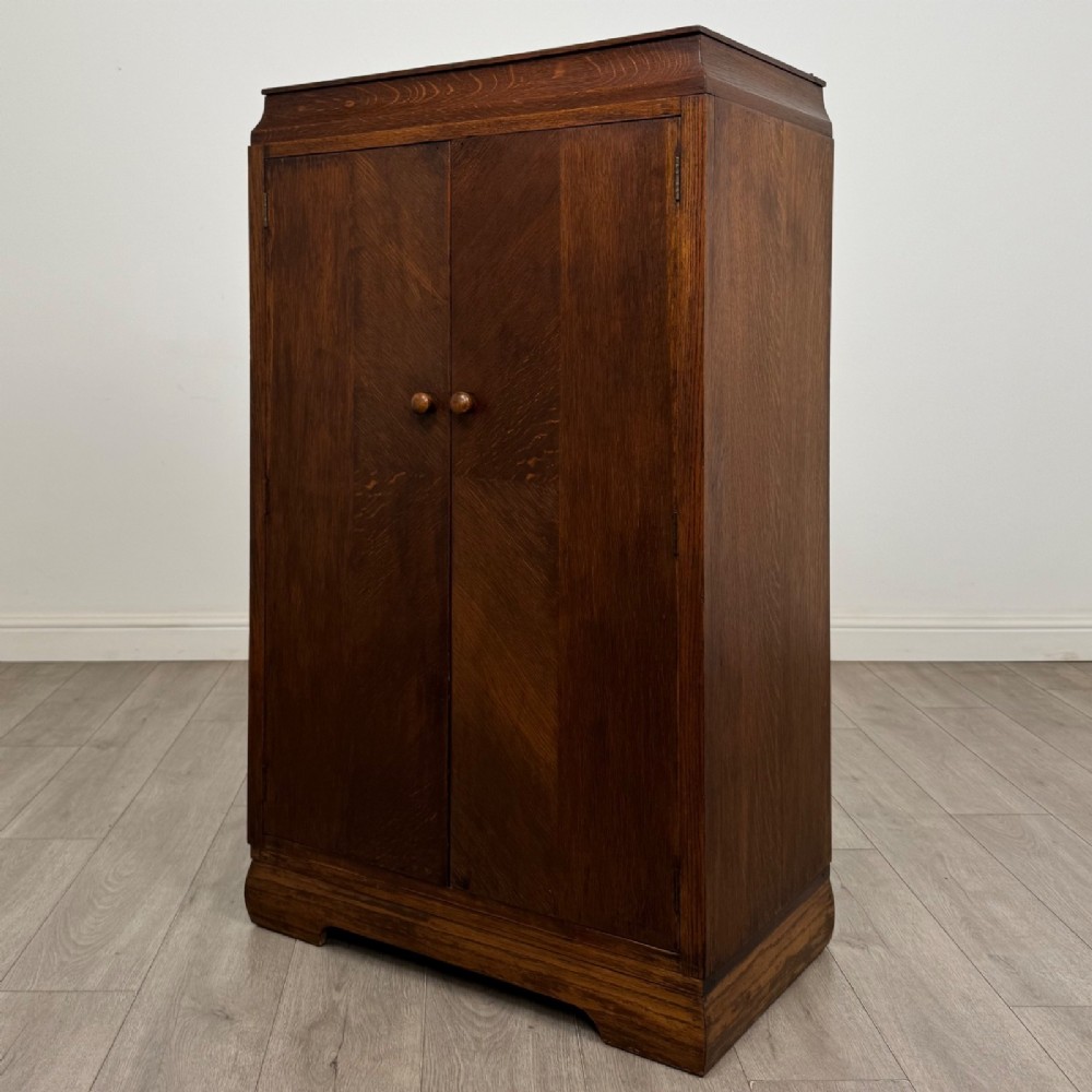 A compact 20th-century oak fitted wardrobe with two doors featuring diagonal grain veneering, turned wooden knobs, and a stepped top profile. View III