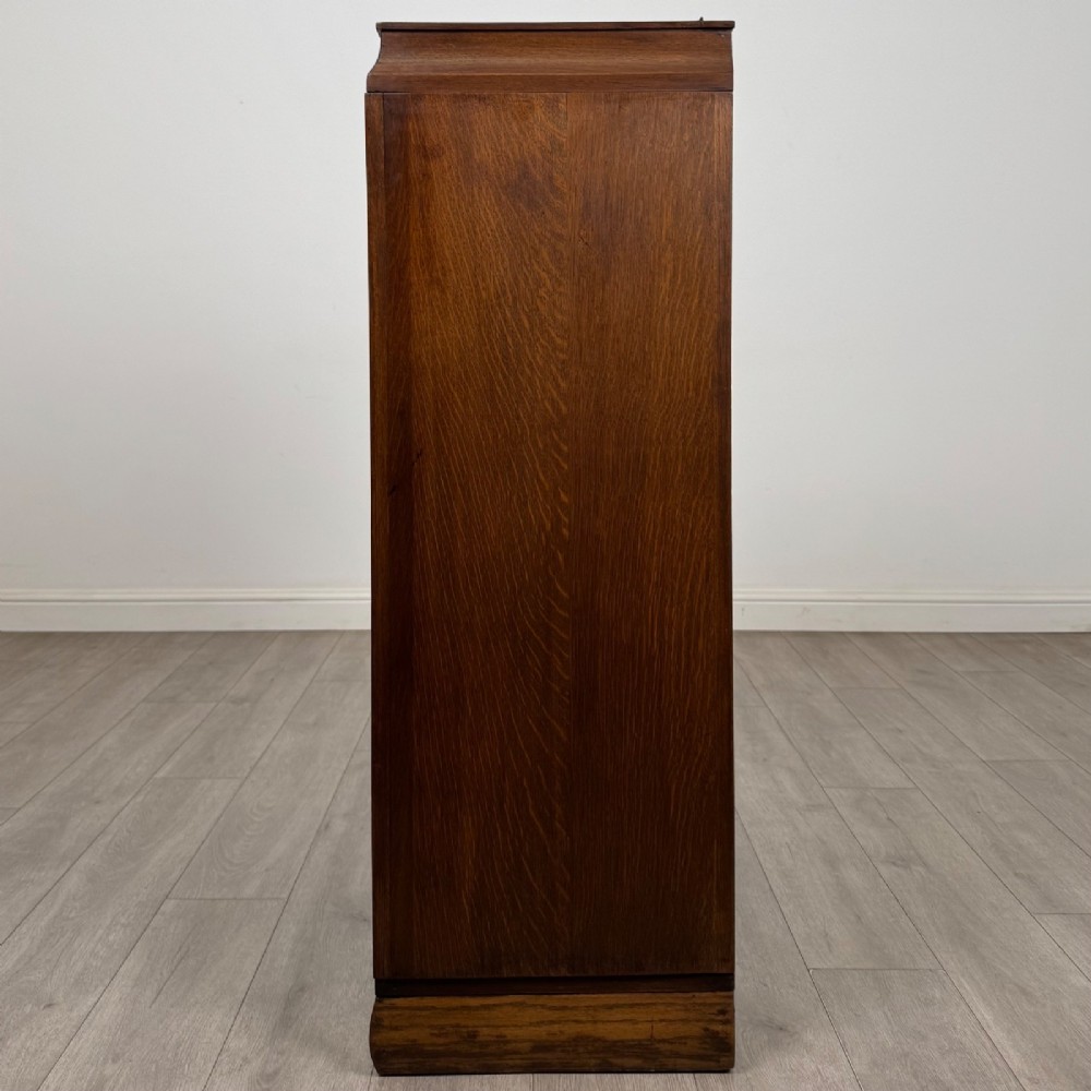 A compact 20th-century oak fitted wardrobe with two doors featuring diagonal grain veneering, turned wooden knobs, and a stepped top profile. View IV