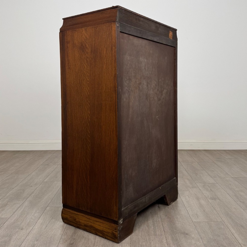 A compact 20th-century oak fitted wardrobe with two doors featuring diagonal grain veneering, turned wooden knobs, and a stepped top profile. View V