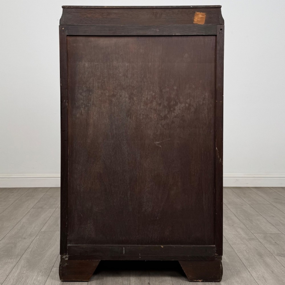A compact 20th-century oak fitted wardrobe with two doors featuring diagonal grain veneering, turned wooden knobs, and a stepped top profile. View VI