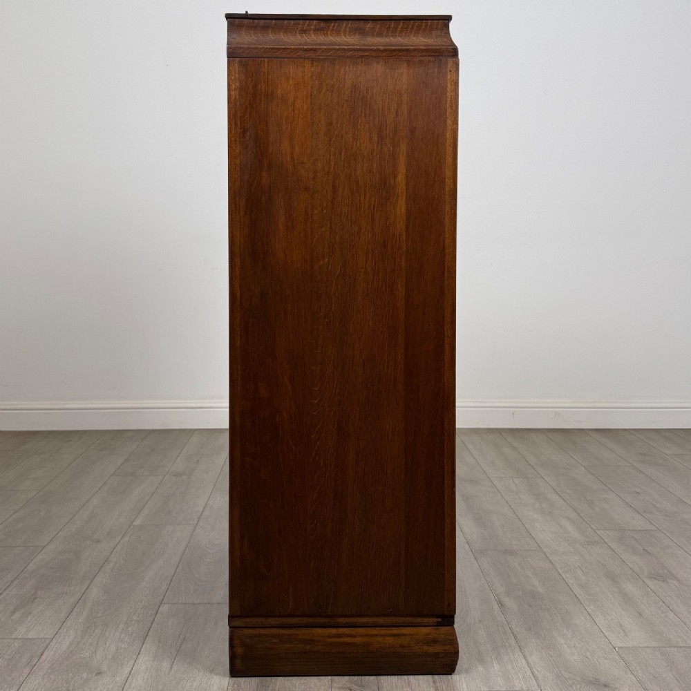 A compact 20th-century oak fitted wardrobe with two doors featuring diagonal grain veneering, turned wooden knobs, and a stepped top profile. View VIII