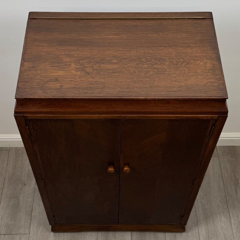 A compact 20th-century oak fitted wardrobe with two doors featuring diagonal grain veneering, turned wooden knobs, and a stepped top profile. View X