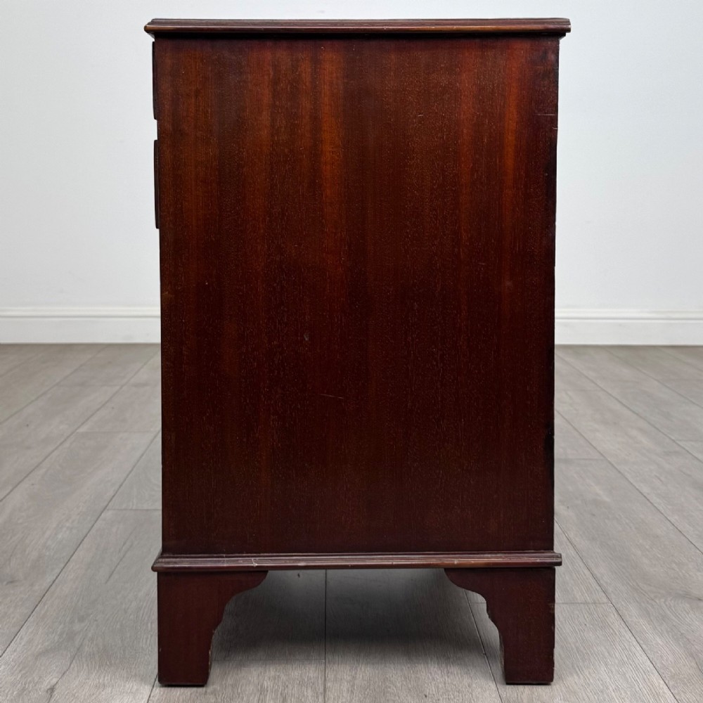 A nineteenth-century dark mahogany small cupboard featuring two drawers with brass swan-neck handles above a double-door compartment set on bracket feet. View IV