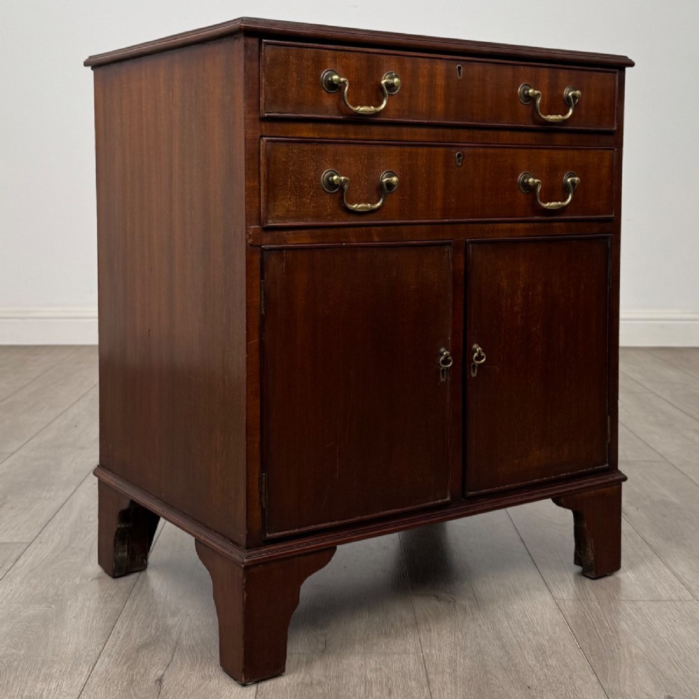 A nineteenth-century dark mahogany small cupboard featuring two drawers with brass swan-neck handles above a double-door compartment set on bracket feet. View IX