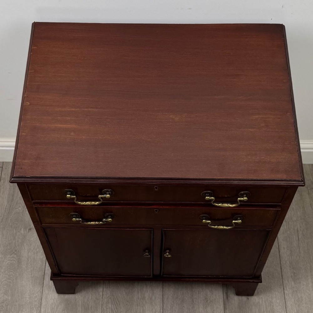 A nineteenth-century dark mahogany small cupboard featuring two drawers with brass swan-neck handles above a double-door compartment set on bracket feet. View X