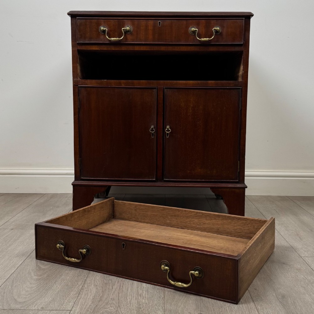 A nineteenth-century dark mahogany small cupboard featuring two drawers with brass swan-neck handles above a double-door compartment set on bracket feet. View XI