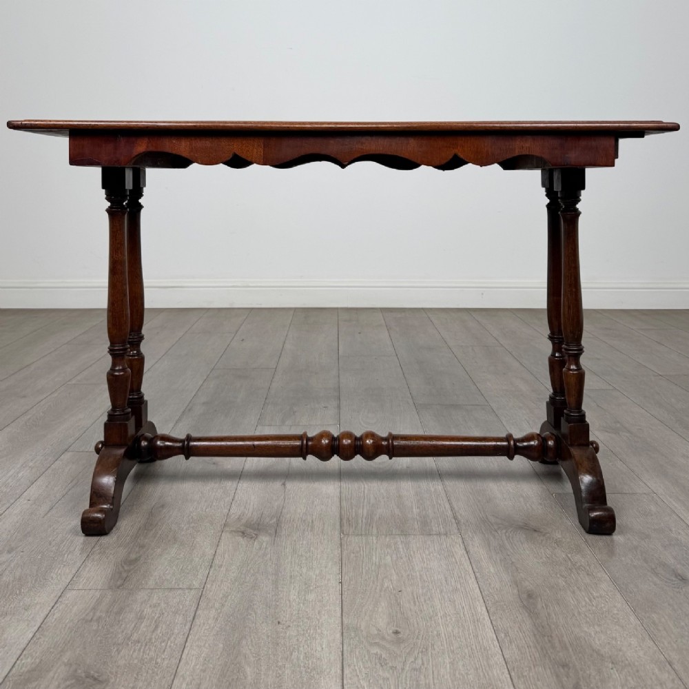 A 19th-century Victorian mahogany side table featuring a rectangular top with a scalloped apron, turned twin-column supports, a central turned stretcher, and curved feet.