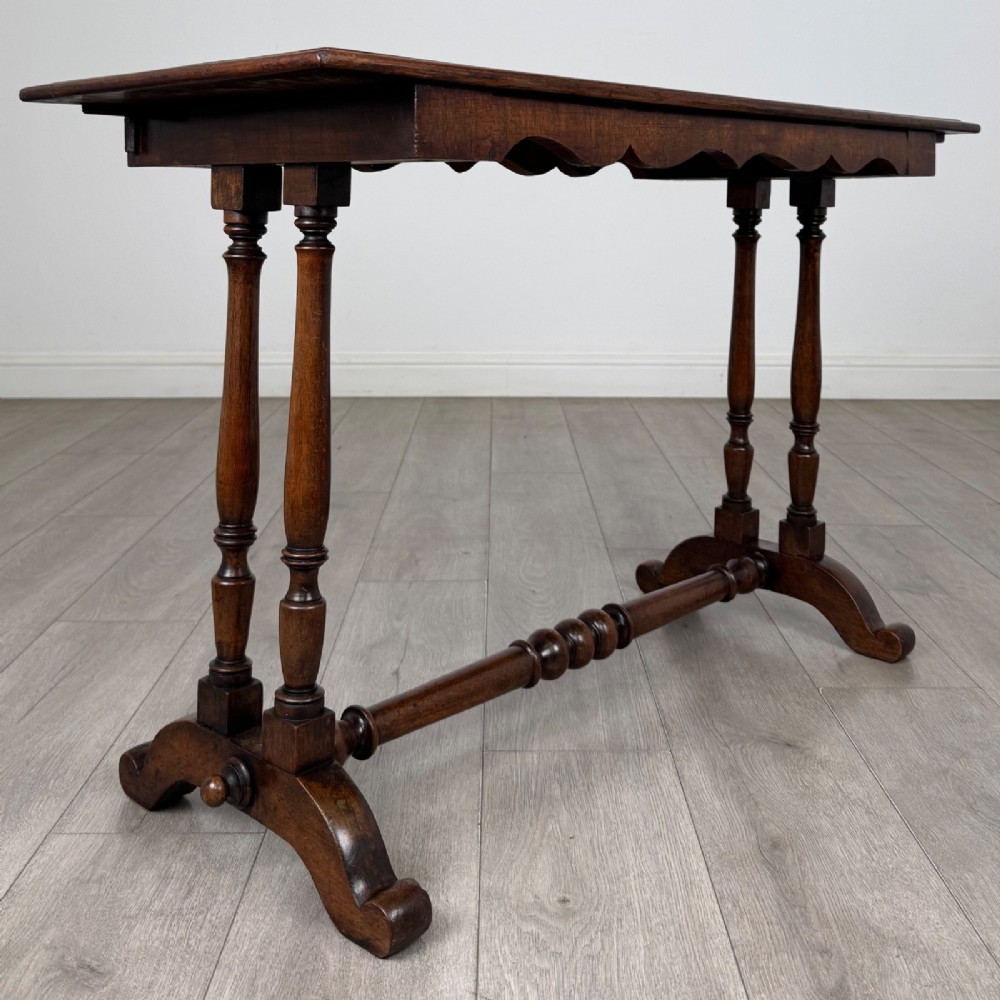A 19th-century Victorian mahogany side table featuring a rectangular top with a scalloped apron, turned twin-column supports, a central turned stretcher, and curved feet. View IV