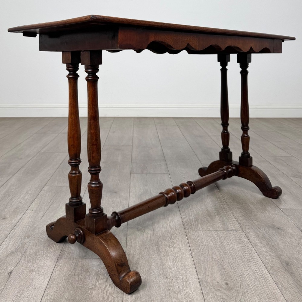 A 19th-century Victorian mahogany side table featuring a rectangular top with a scalloped apron, turned twin-column supports, a central turned stretcher, and curved feet. View VIII