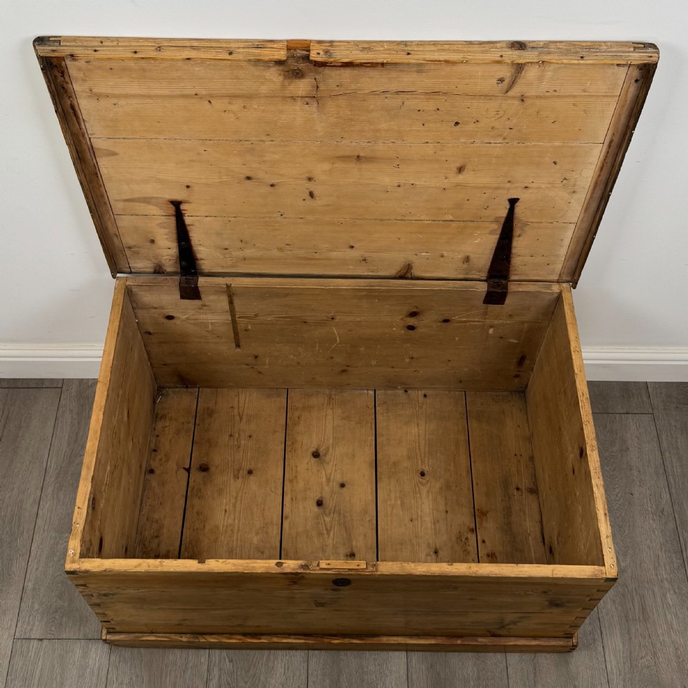 A rectangular nineteenth-century rustic pine blanket box with visible hand-cut dovetail joints, a central keyhole escutcheon, and a moulded base. View X