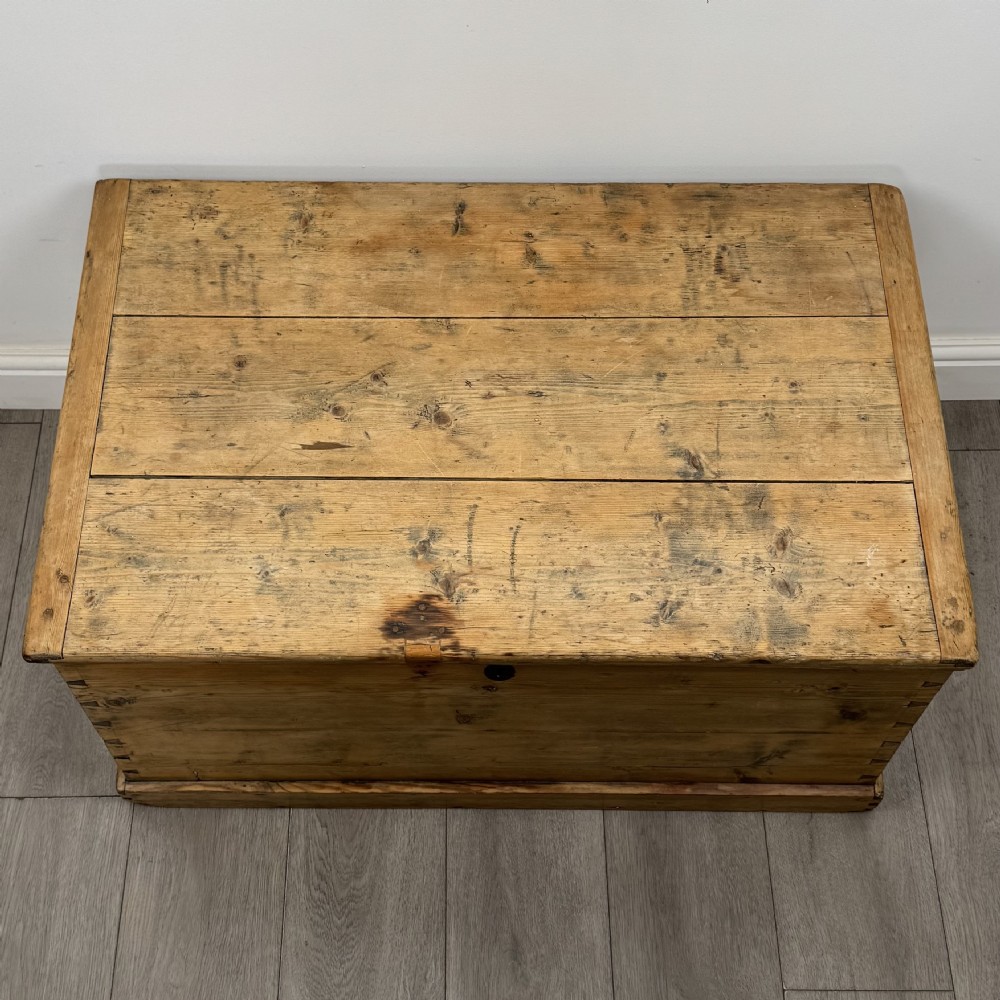 A rectangular nineteenth-century rustic pine blanket box with visible hand-cut dovetail joints, a central keyhole escutcheon, and a moulded base. View IX