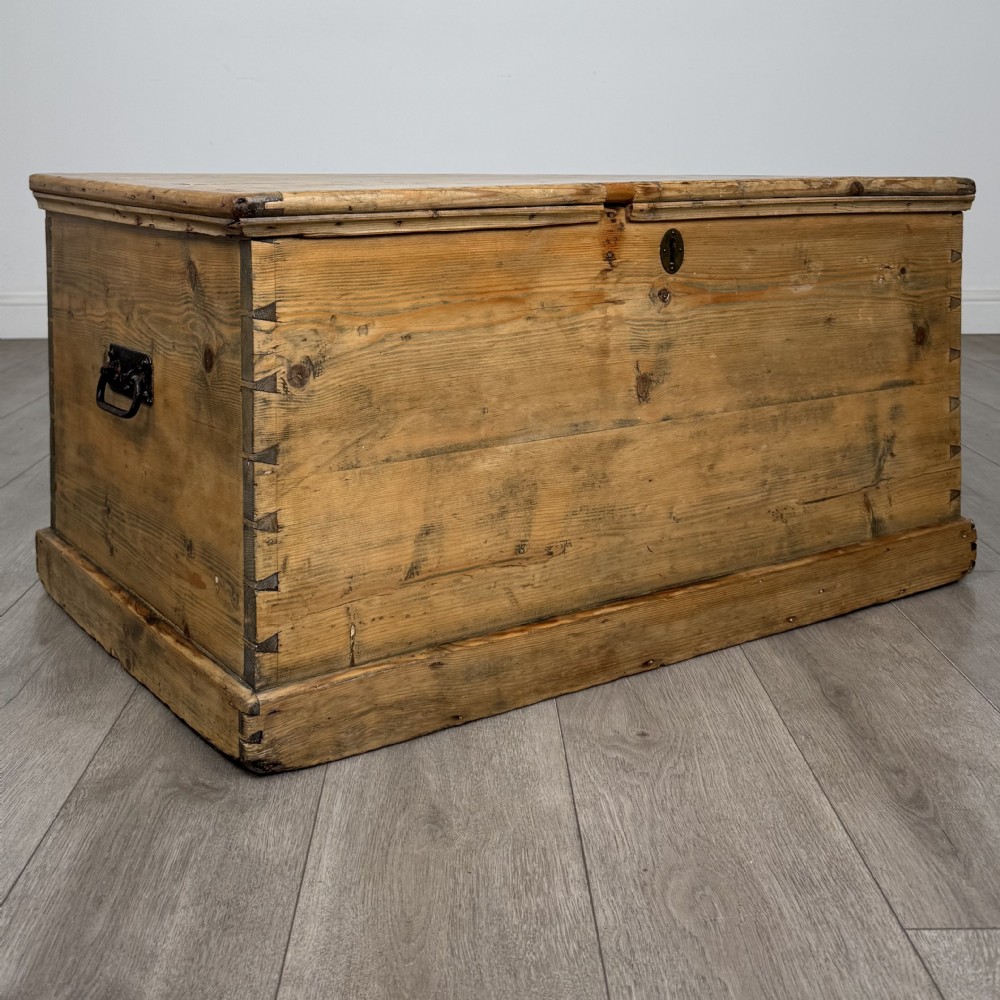 A rectangular nineteenth-century rustic pine blanket box with visible hand-cut dovetail joints, a central keyhole escutcheon, and a moulded base. View VIII