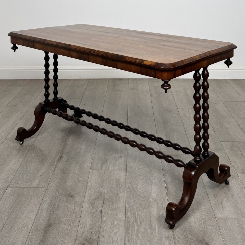 A Victorian dark wood side table with a polished rectangular top, corner drop finials, double bobbin-turned legs, a twin bobbin stretcher, and splayed feet with brass castors.
