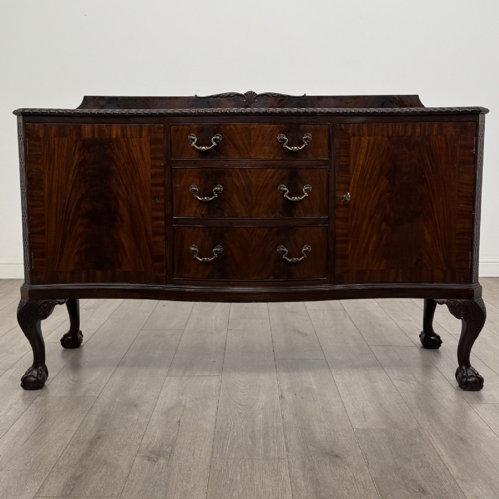 An Edwardian mahogany sideboard featuring three central drawers flanked by two cupboard doors, resting on cabriole legs with claw and ball feet.