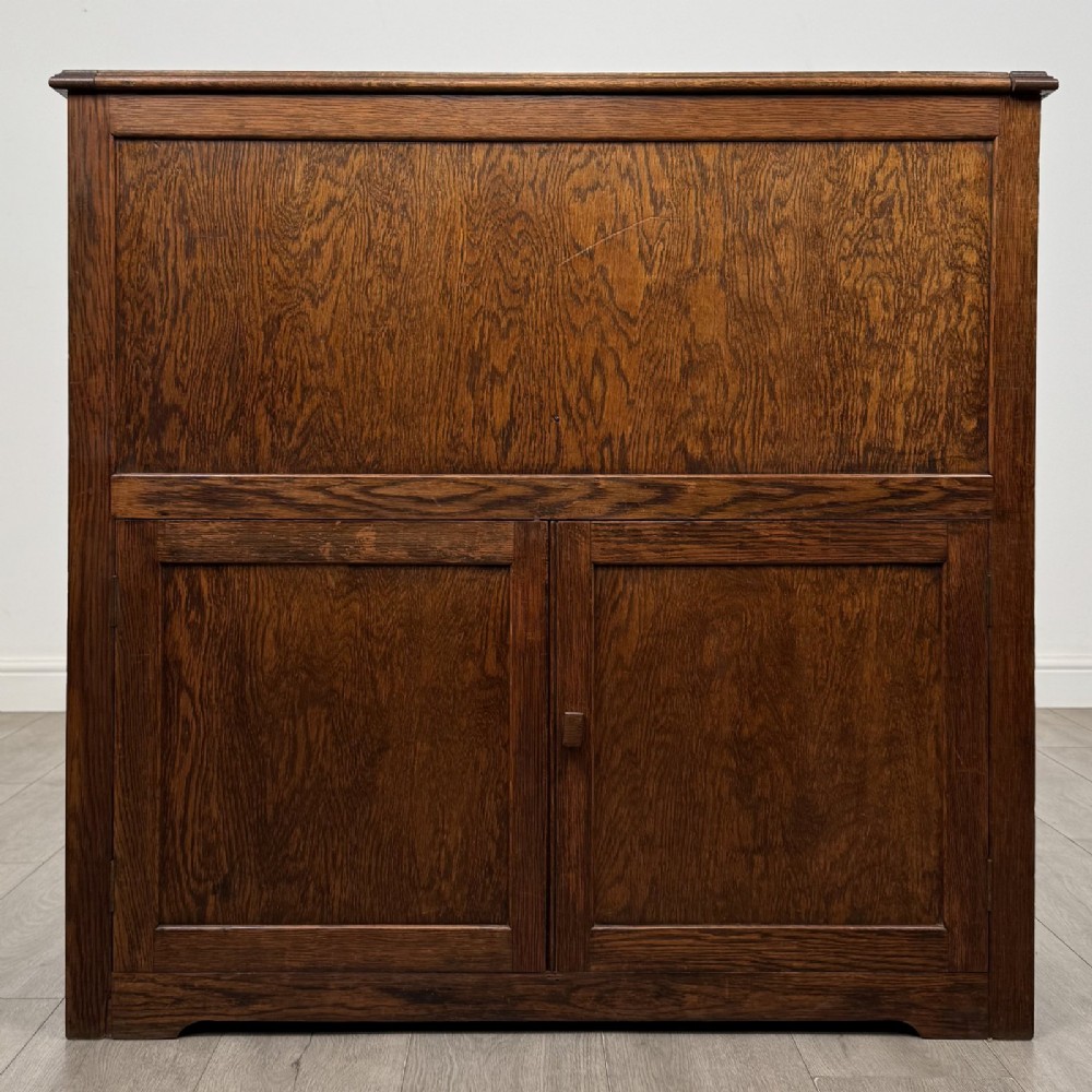 An antique dark oak fitted cupboard featuring a smooth top section above two panelled lower cupboard doors.