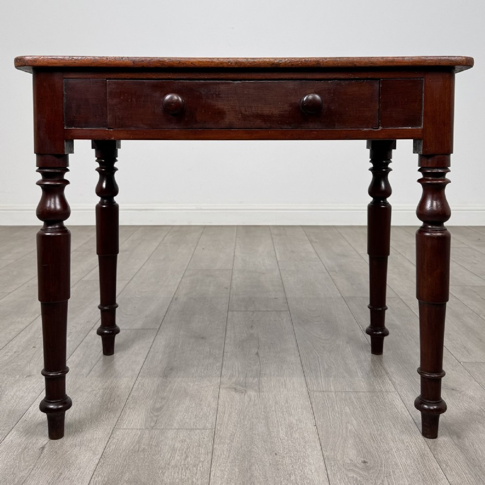 A Victorian mahogany writing table featuring a rectangular top, a single drawer with two wooden knobs, and four turned legs.