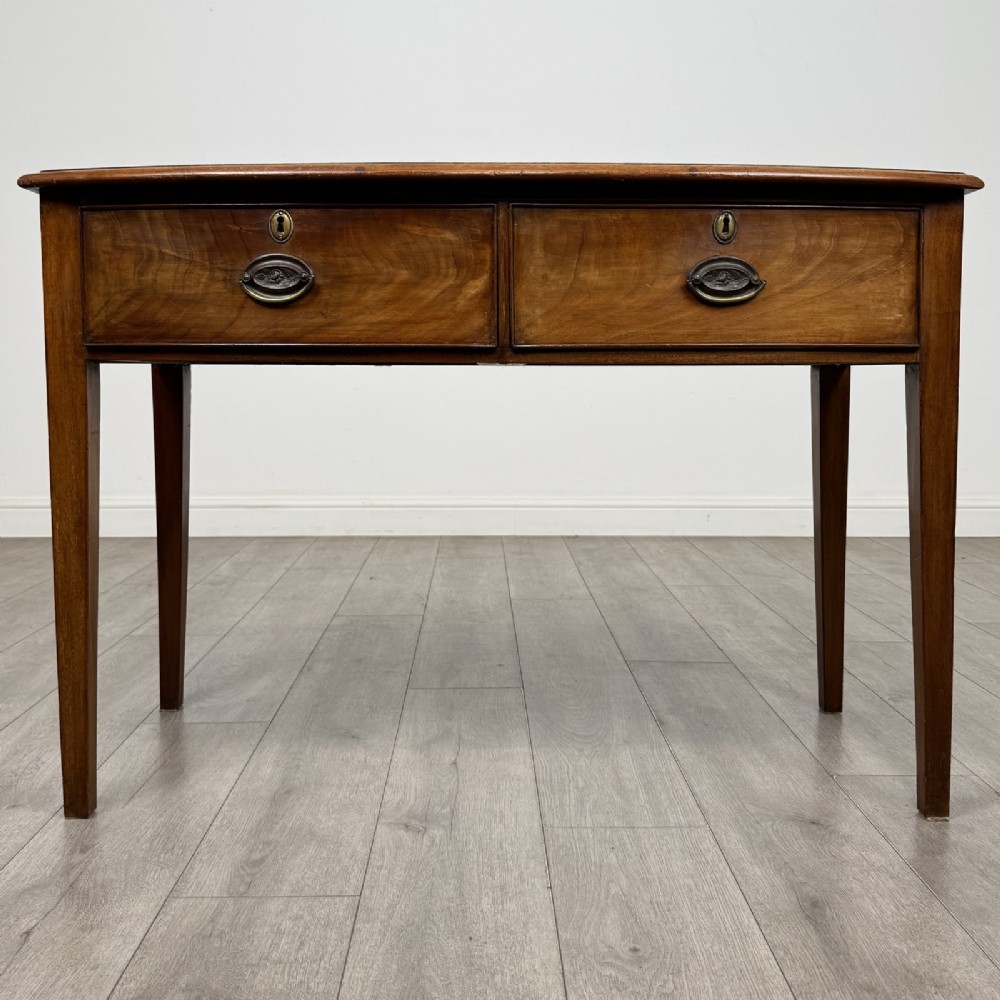 An antique Georgian style mahogany side table featuring two front drawers with oval brass handles and four tapered square legs.