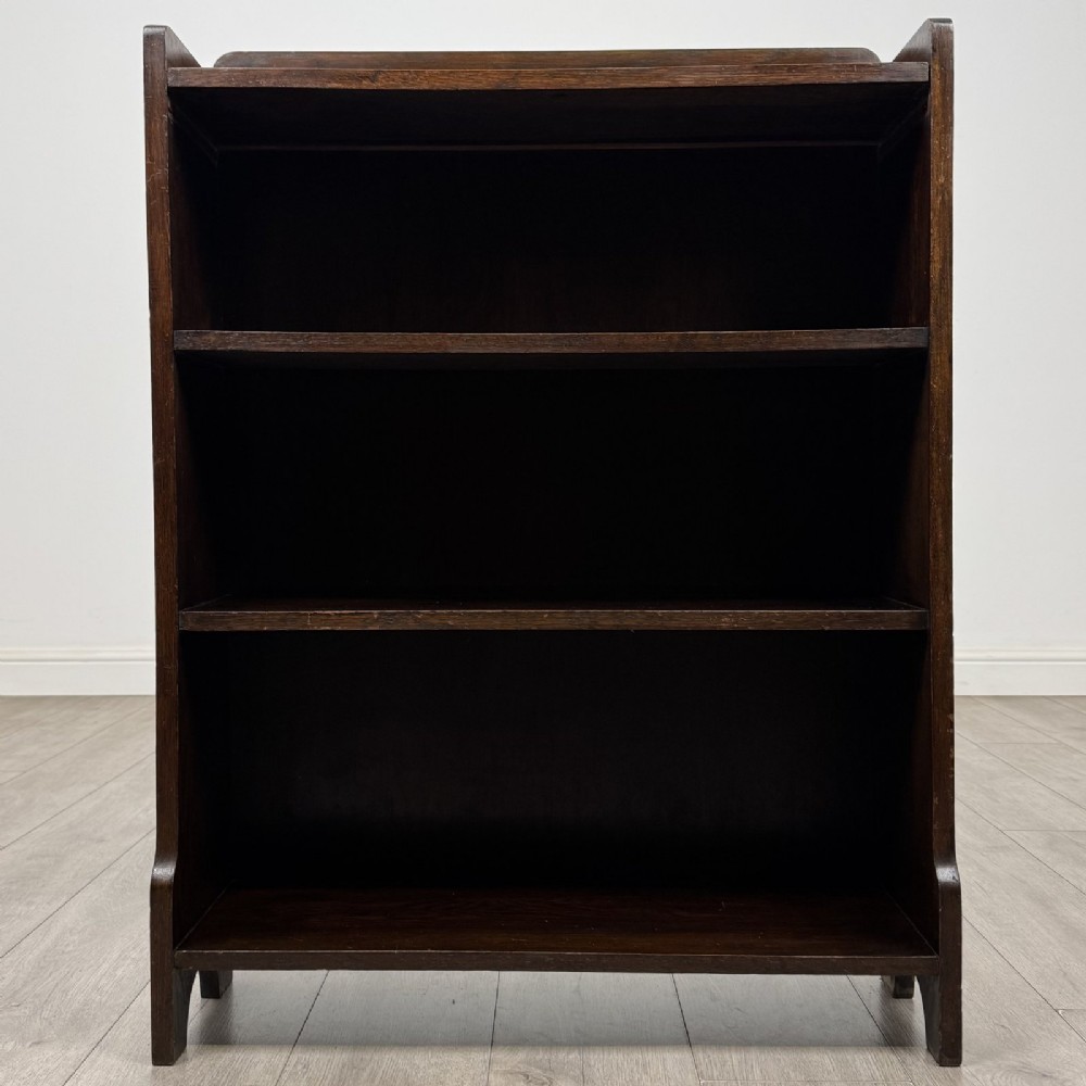 A dark brown Edwardian oak open bookcase featuring two internal fixed shelves and simple vertical side panels.