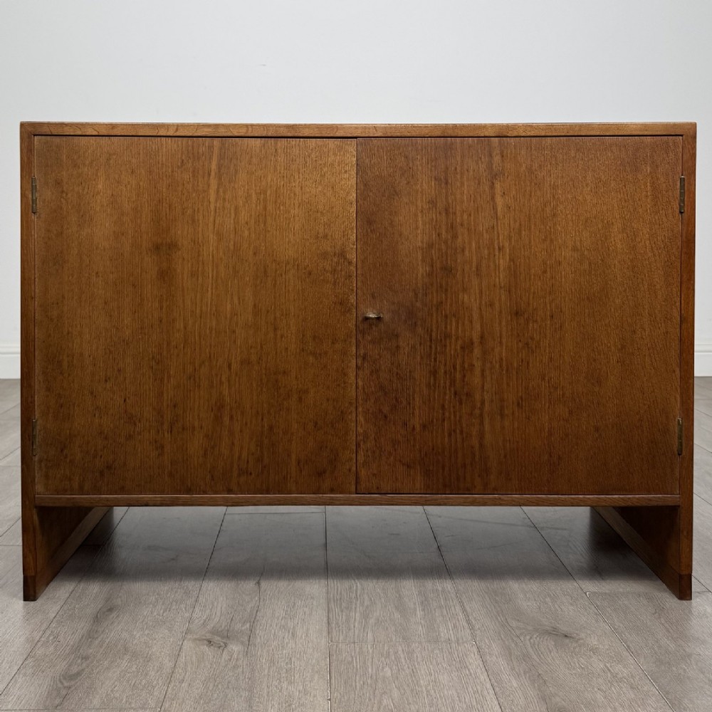 A mid-century modern Danish oak cupboard featuring two flush panel doors and solid side supports.