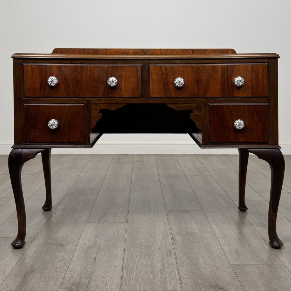 An Edwardian walnut writing table featuring four drawers with blue and white patterned ceramic knobs, raised on cabriole legs.