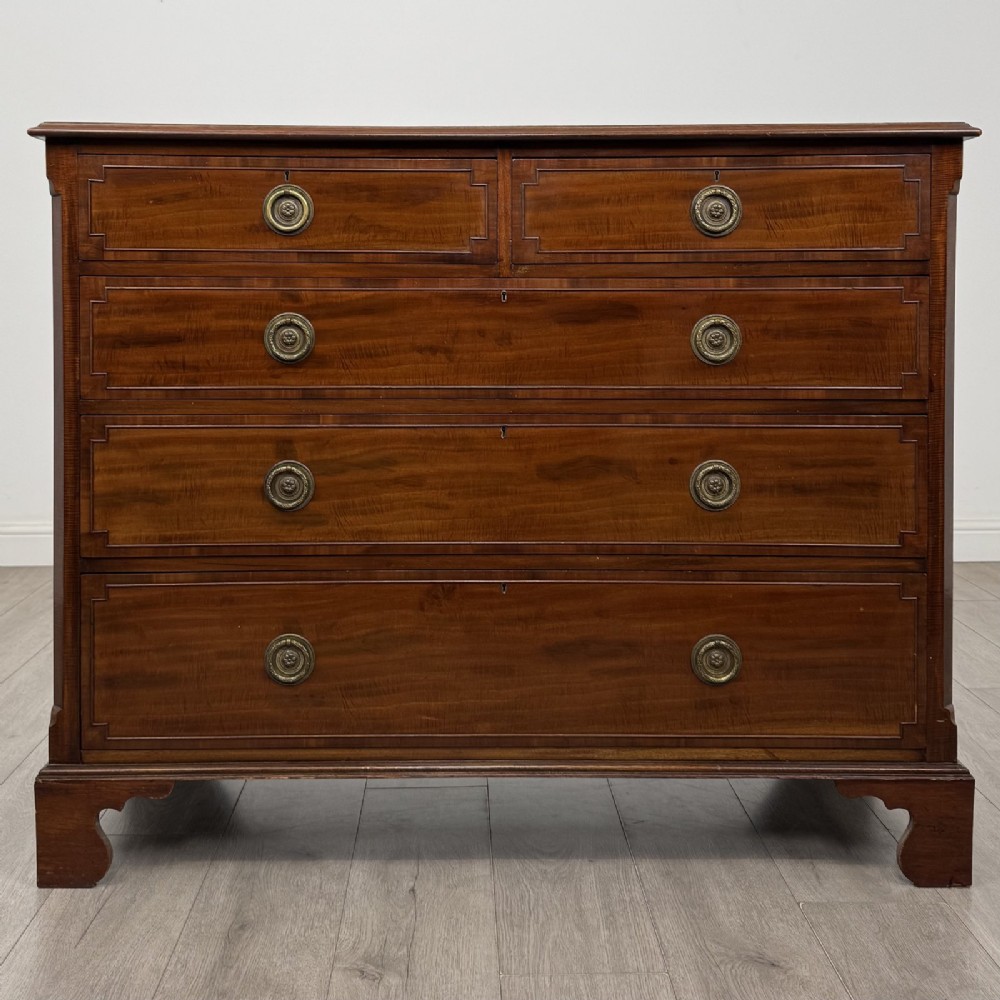 A Georgian style mahogany chest of drawers featuring a two-over-three drawer arrangement, brass ring handles, and bracket feet.