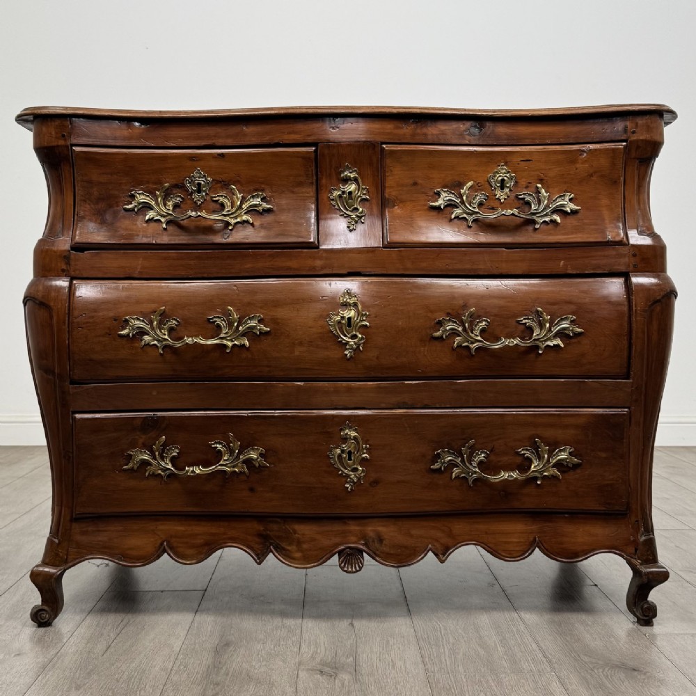 An 18th-century French Louis XV bombe commode in warm brown cherrywood featuring ornate brass handles and cabriole legs.
