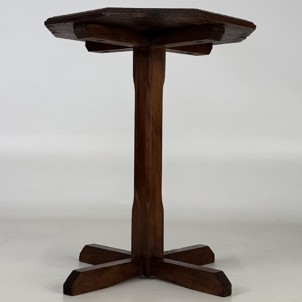 An antique dark oak side table featuring an octagonal top, a central chamfered pedestal, and a four-point cruciform base.