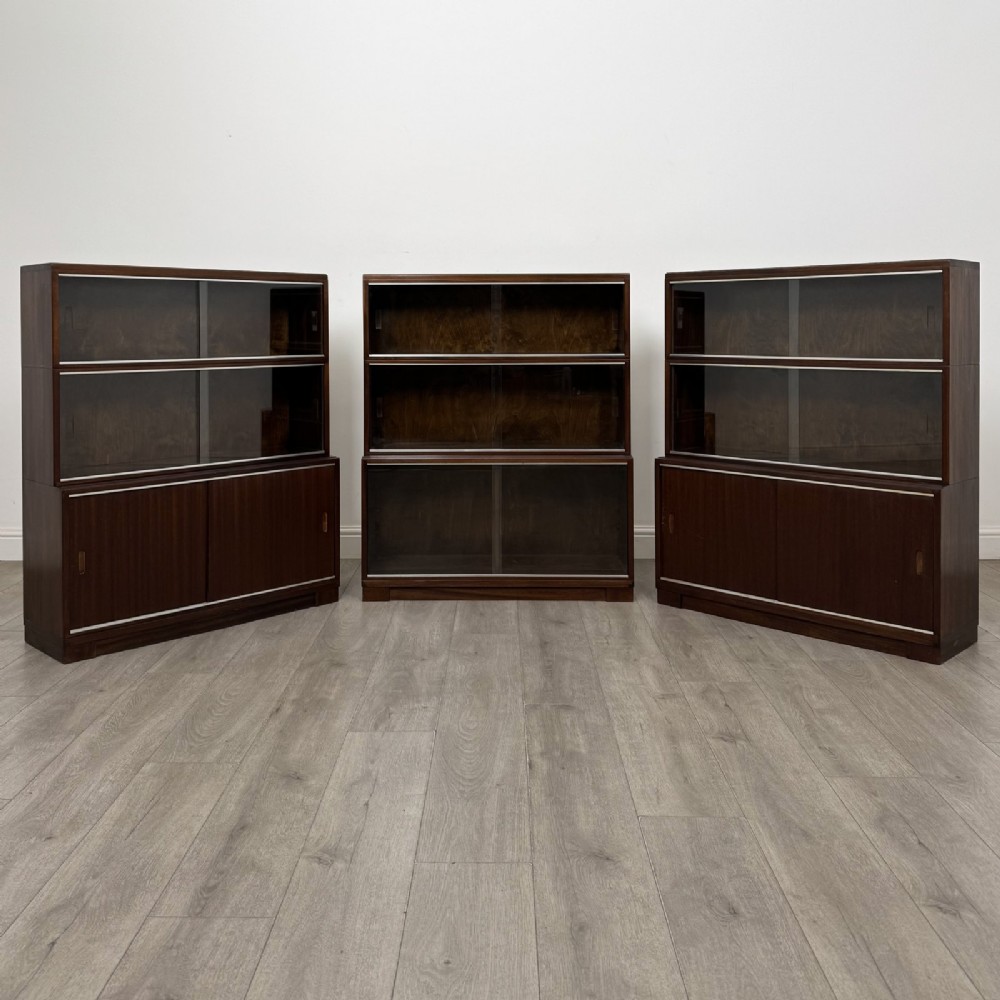 A set of three dark mahogany modular cabinets featuring sliding glass doors and lower wood storage compartments.