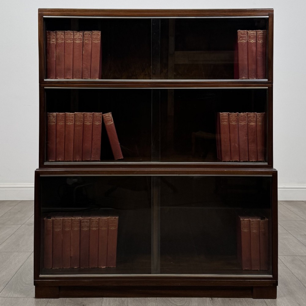 A dark mahogany three-tier display cabinet featuring sliding glass doors and a rectangular plinth base.