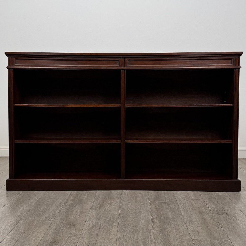 A large 20th-century dark mahogany open bookcase featuring two wide bays with adjustable shelving and a solid plinth base.