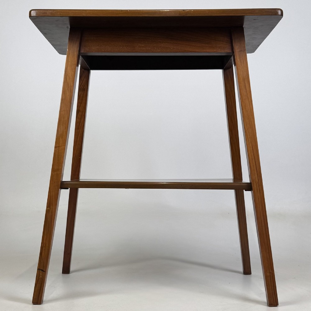 An Edwardian figured walnut lamp table featuring a square top, lower tier shelf, and tapered splayed legs.