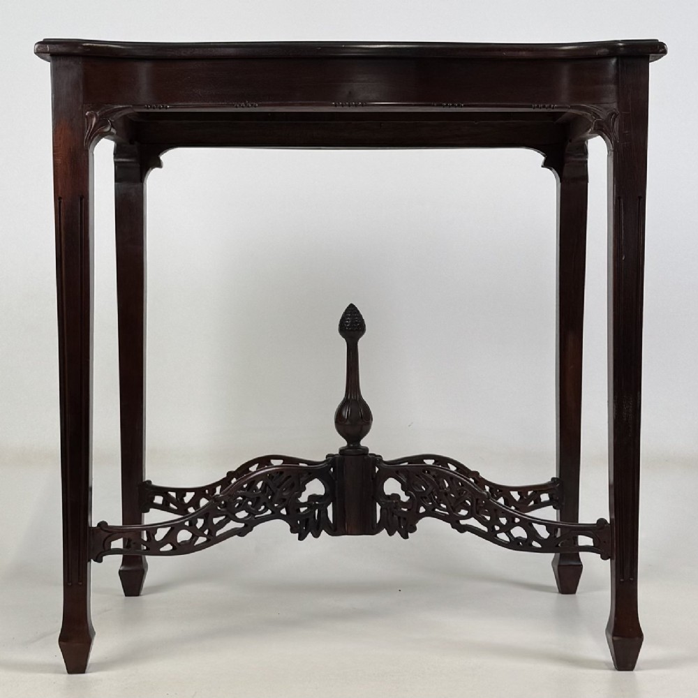 An Edwardian mahogany side table with four square tapered legs, a carved fretwork X-stretcher, and a central turned finial.